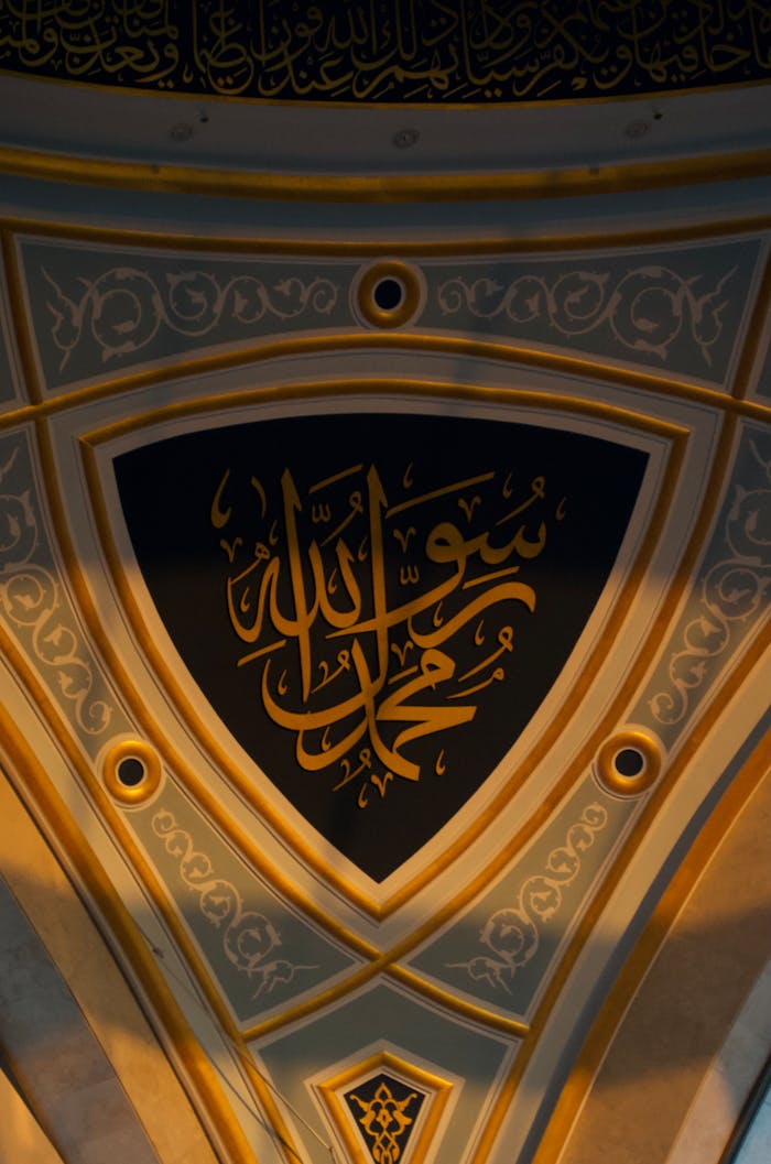 Intricate Arabic calligraphy on mosque ceiling, showcasing Islamic art and architecture.